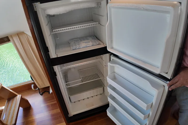 Slide: The Image of 2003 Navigator Rival refrigerator, open with empty shelves, in a wooden-floored room. - 28