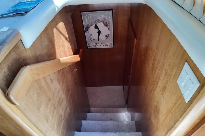 Slide: The Image of Wooden staircase inside 2003 Navigator Rival yacht, featuring a vintage poster on the wall. - 30