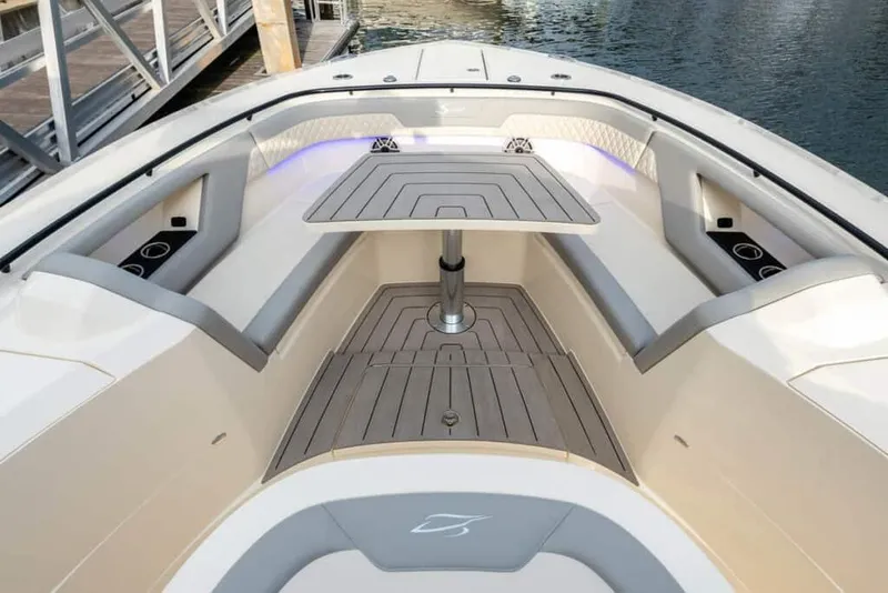 Slide: The Image of Manufacturer Provided Image: 2025 Scout 377 LXF boat interior with seating and table, docked by the water. - 5