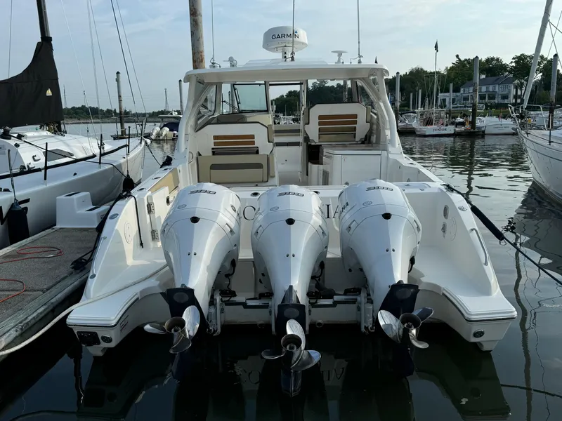 Slide: The Image of 2021 Pursuit DC 365 boat with triple outboard engines docked at a marina. - 4