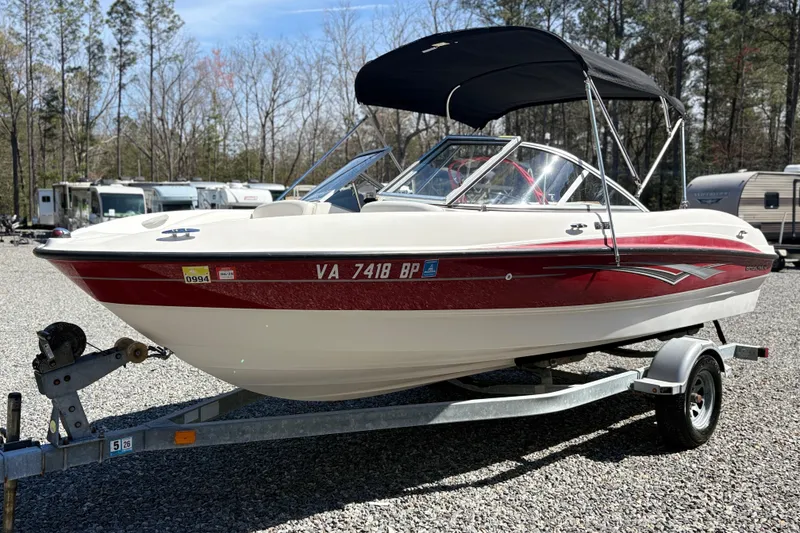 The Image of 2009 Bayliner 185 Bowrider boat on trailer, parked outdoors with trees in background. - 0