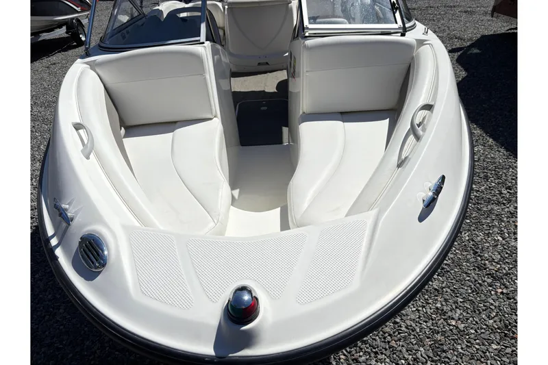 Slide: The Image of 2009 Bayliner 185 Bowrider boat with white interior, parked on gravel. - 10