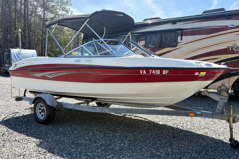 Slide: The Image of 2009 Bayliner 185 Bowrider boat on trailer, parked outdoors with RV in background. - 3