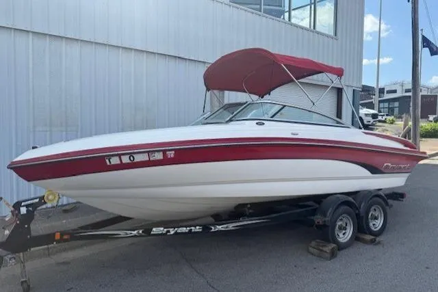 The Image of 2011 Bryant 210 boat with red canopy on trailer, parked outdoors. - 0