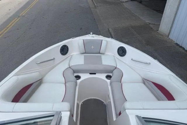 Slide: The Image of 2011 Bryant 210 boat interior with white and red seating, docked near a street. - 10
