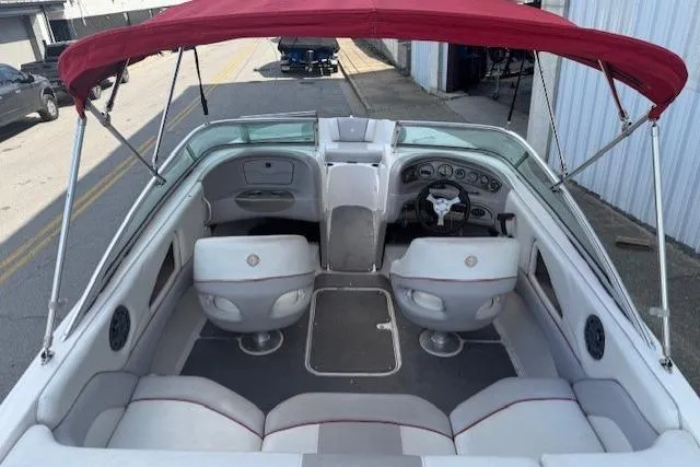 Slide: The Image of 2011 Bryant 210 boat interior with red canopy, white seating, and dashboard view. - 26