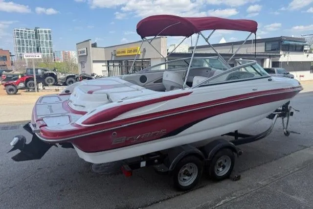 Slide: The Image of 2011 Bryant 210 boat with red and white design on a trailer, parked outdoors. - 3