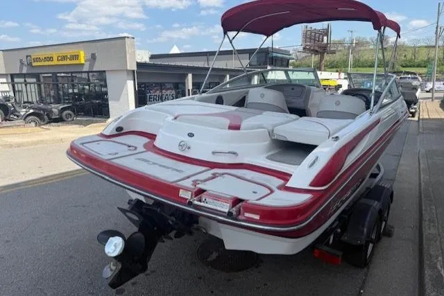 Slide: The Image of 2011 Bryant 210 boat with red and white design, parked near a dealership. - 6