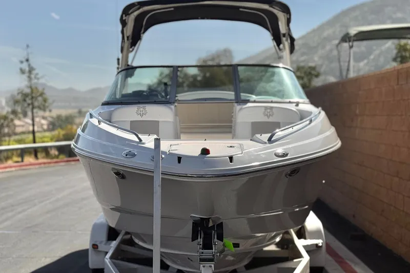Slide: The Image of 2011 Chaparral 267 SSX boat on trailer, parked outdoors with scenic mountain backdrop. - 2