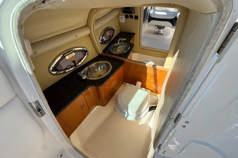 Slide: The Image of 2011 Chaparral 267 SSX boat interior with compact bathroom, sink, and porthole windows. - 31