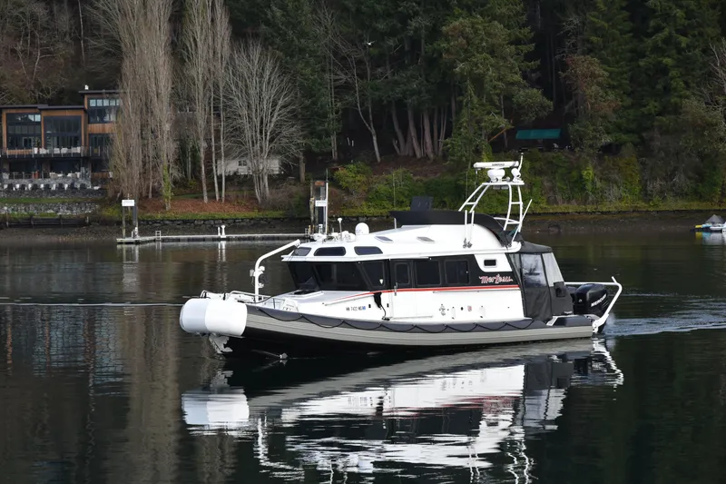 Slide: The Image of 2005 SAFE Boats 33 Full Cabin on calm water near forested shoreline. - 2