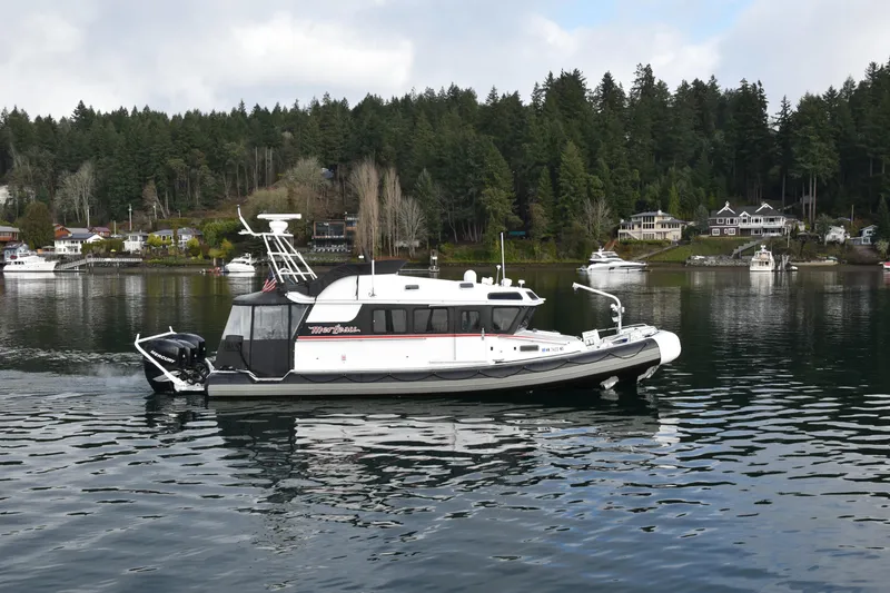 Slide: The Image of 2005 SAFE Boats 33 Full Cabin on calm water, surrounded by forested shoreline and houses. - 3