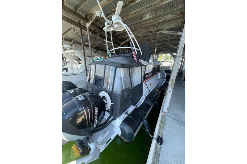 Slide: The Image of 2005 SAFE Boats 33 Full Cabin docked under a covered marina with twin Mercury engines. - 81