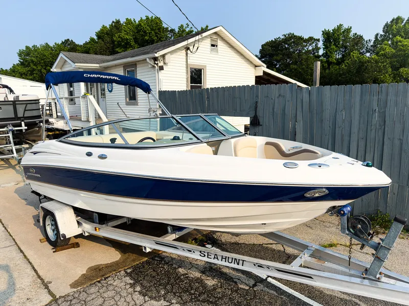 The Image of 2007 Chaparral 190 SSi boat on trailer, parked near a house with a blue fence. - 1