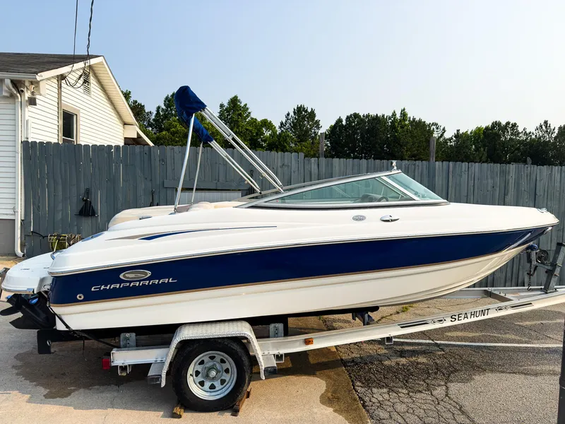 Slide: The Image of 2007 Chaparral 190 SSi boat on trailer, parked near a house with a wooden fence. - 2