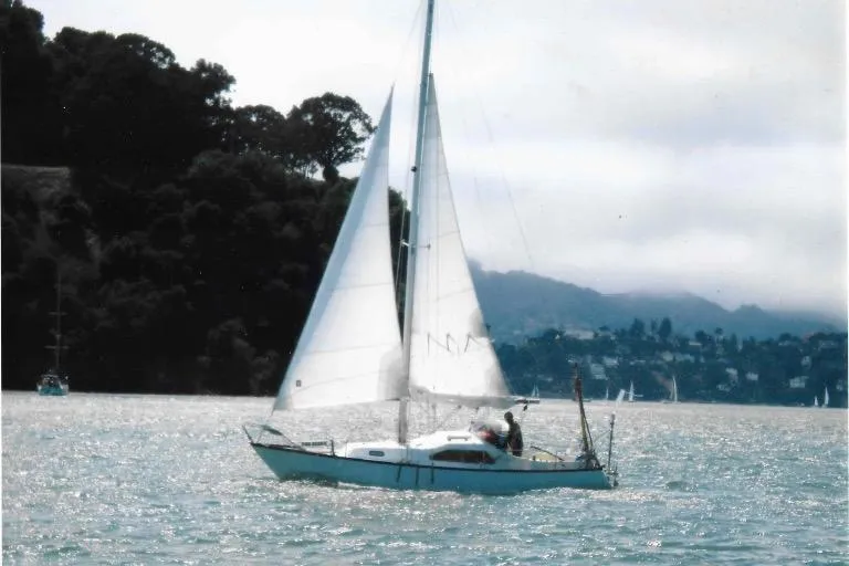 The Image of 1970 King's Cruiser 29 sailboat gliding on a serene lake with distant hills. - 0