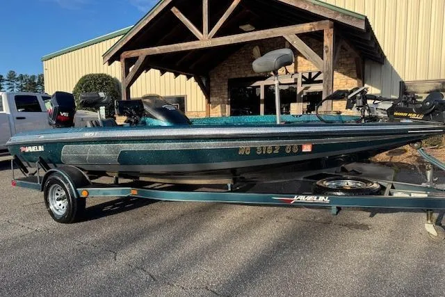 The Image of 1994 Javelin 389T boat on trailer, parked outside a building. - 1