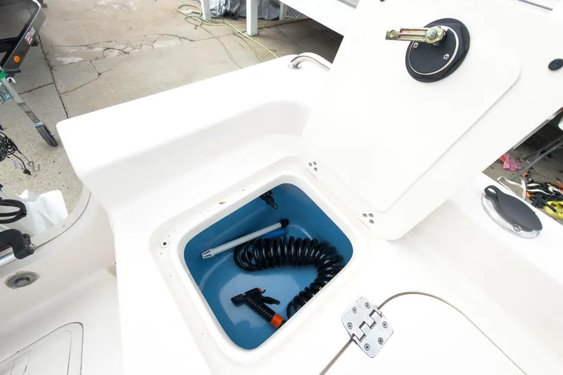Slide: The Image of 2025 Carolina Skiff 21 Ultra Elite storage compartment with coiled hose and accessories. - 30