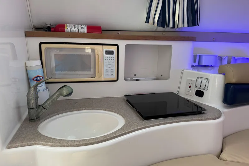 Slide: The Image of Compact kitchen area in a 2005 Century 3200 Walk-Around boat with sink, microwave, and stove. - 15