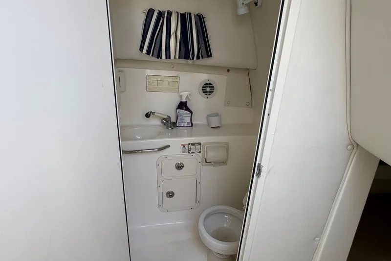 Slide: The Image of 2005 Century 3200 Walk-Around boat bathroom with sink, toilet, and striped curtain. - 20
