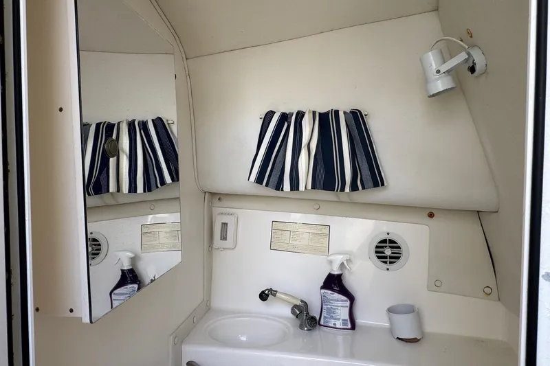 Slide: The Image of Compact bathroom in 2005 Century 3200 Walk-Around boat with striped curtain and cleaning supplies. - 21