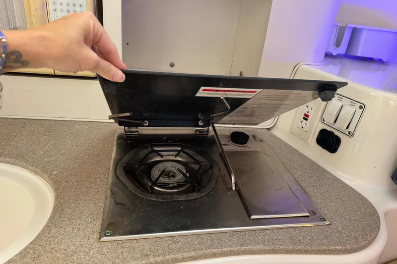 Slide: The Image of Hand lifting stove cover in 2005 Century 3200 Walk-Around boat kitchen. - 23