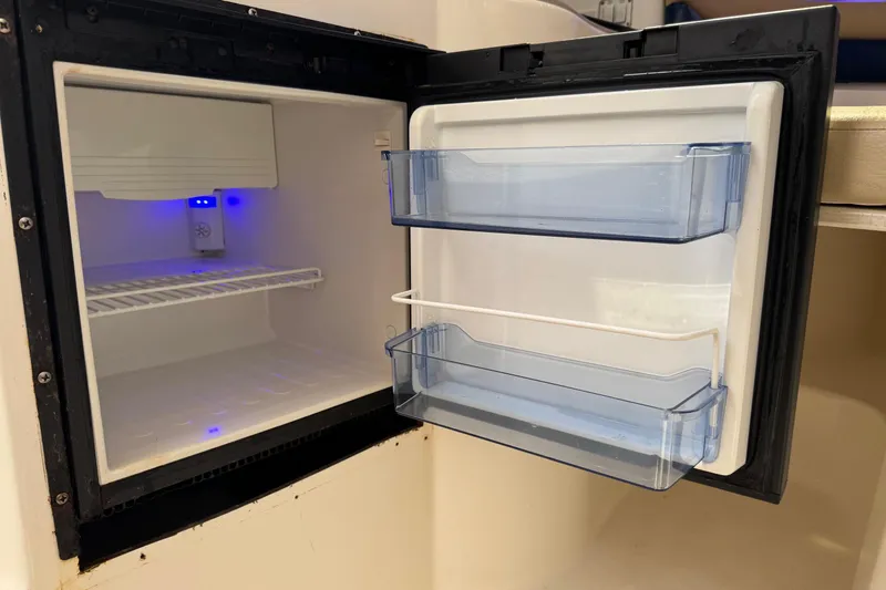Slide: The Image of Open mini fridge inside a 2005 Century 3200 Walk-Around boat, showing interior shelves. - 26