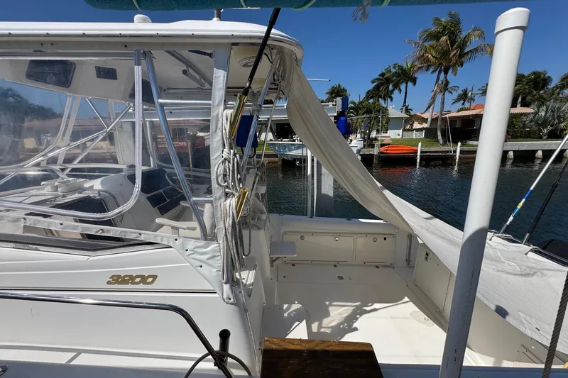 Slide: The Image of 2005 Century 3200 Walk-Around boat docked by waterfront homes, clear skies. - 4