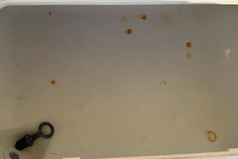 Slide: The Image of Interior of a 2005 Century 3200 Walk-Around boat showing rust spots and a drain plug. - 78