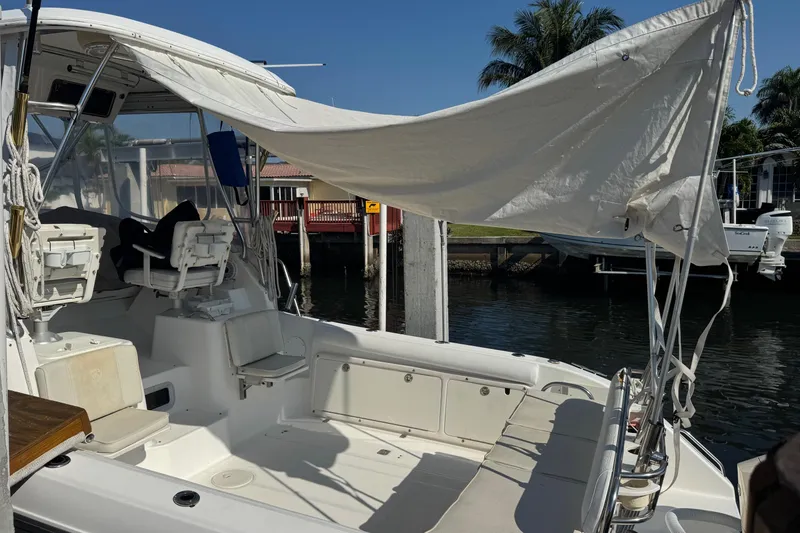 Slide: The Image of 2005 Century 3200 Walk-Around boat docked, featuring seating and canopy, under clear skies. - 96