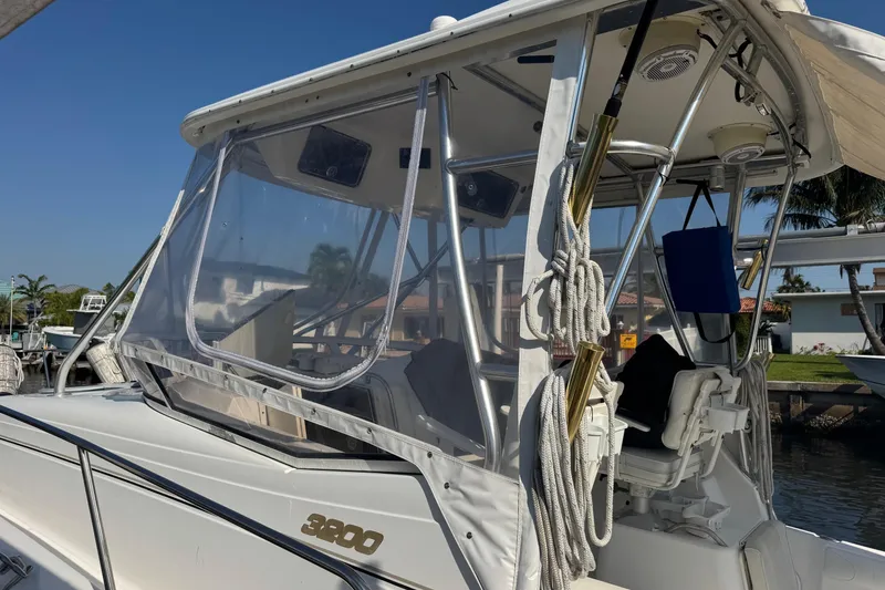 Slide: The Image of 2005 Century 3200 Walk-Around boat docked, featuring clear enclosure and fishing gear. - 97