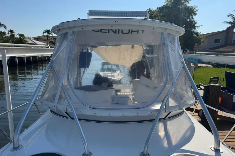 Slide: The Image of 2005 Century 3200 Walk-Around boat docked by waterfront homes, featuring clear enclosure. - 99