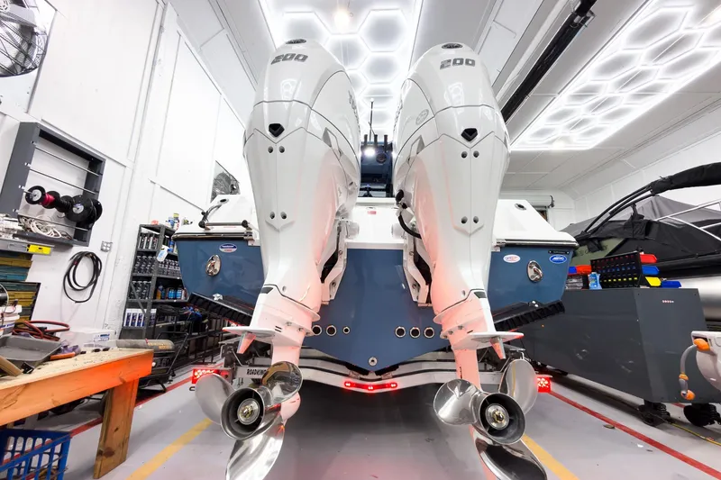 Slide: The Image of 2026 Tidewater 272 CC Adventure boat with dual outboard engines in a workshop. - 7