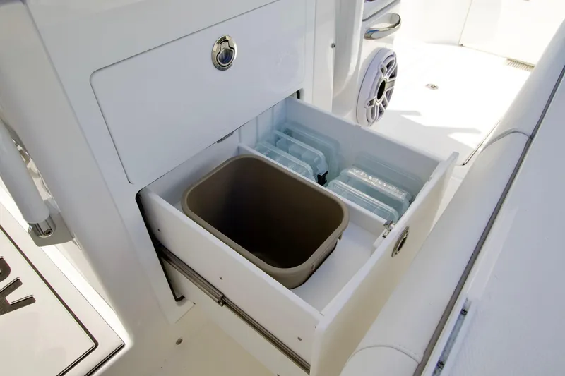 Slide: The Image of 2027 Regulator 35 boat storage compartment with organized containers and a trash bin. - 29