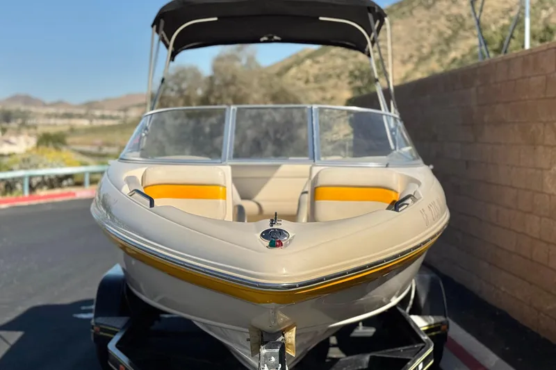 Slide: The Image of 2003 Rinker 192 Captiva Bowrider boat with yellow accents on a trailer. - 2