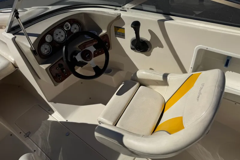 Slide: The Image of 2003 Rinker 192 Captiva Bowrider cockpit with steering wheel and yellow-accented captain's chair. - 22