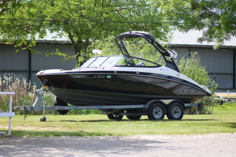 The Image of 2017 Yamaha Boats 212X on trailer, parked outdoors near trees and a building. - 0