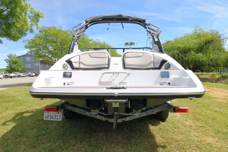 Slide: The Image of 2017 Yamaha Boats 212X on trailer, rear view, parked on grass. - 1