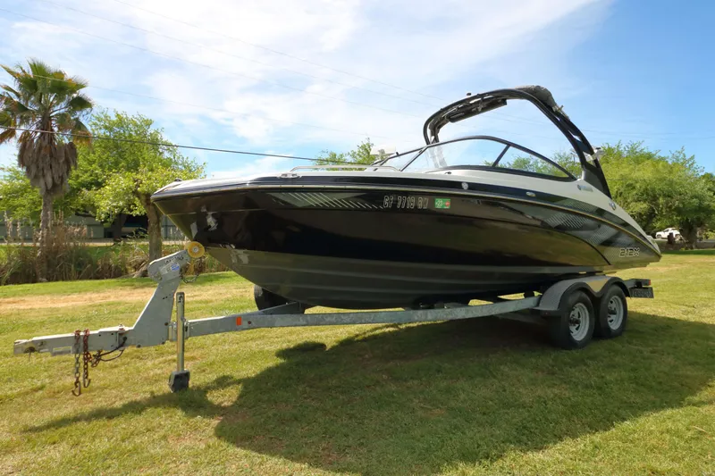 Slide: The Image of 2017 Yamaha Boats 212X on trailer, parked on grass with trees in background. - 3