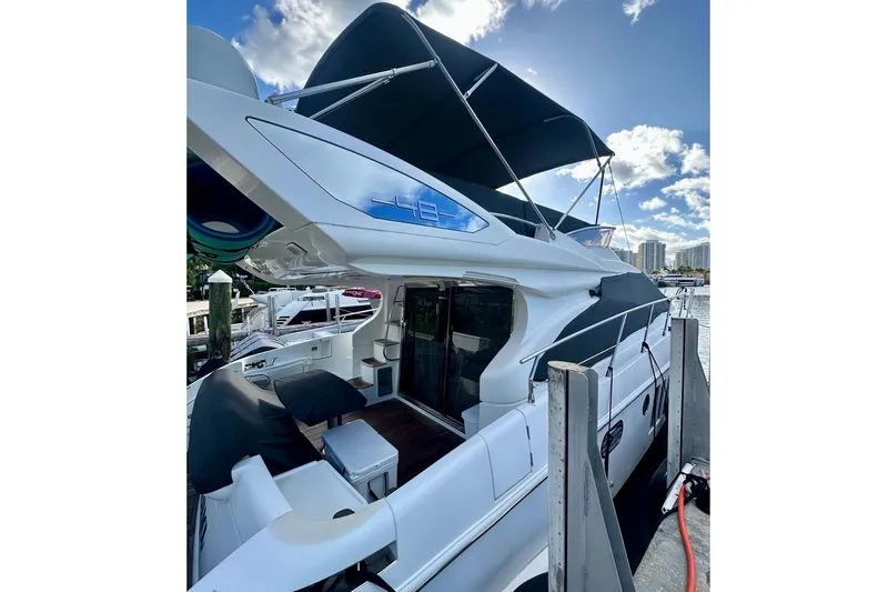 Slide: The Image of 2014 Azimut 48 yacht docked, featuring sleek design and spacious deck under a clear sky. - 4