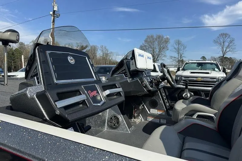 Slide: The Image of 2023 Ranger Z520R boat interior with advanced dashboard and seating, parked outdoors. - 8