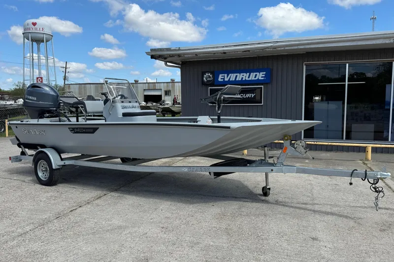 The Image of 2025 SeaArk Shadow 18T boat on trailer, parked outside dealership under blue sky. - 1