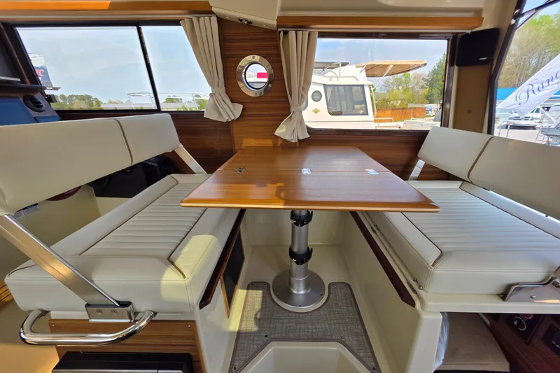 Slide: The Image of Interior of 2026 Ranger Tugs R-27, featuring a cozy dining area with wooden table and cushioned seating. - 11