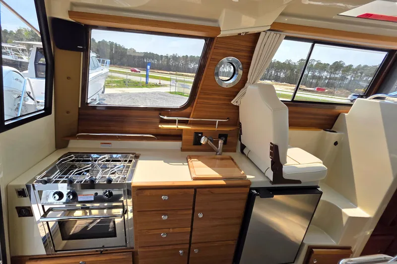 Slide: The Image of Interior of 2026 Ranger Tugs R-27 featuring kitchen and seating area. - 12