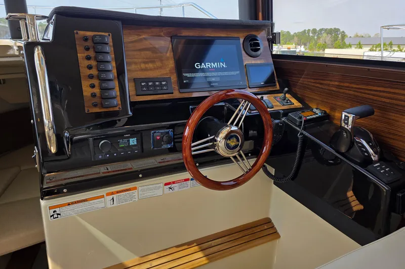 Slide: The Image of 2026 Ranger Tugs R-27 helm with Garmin navigation, wood accents, and modern controls. - 13