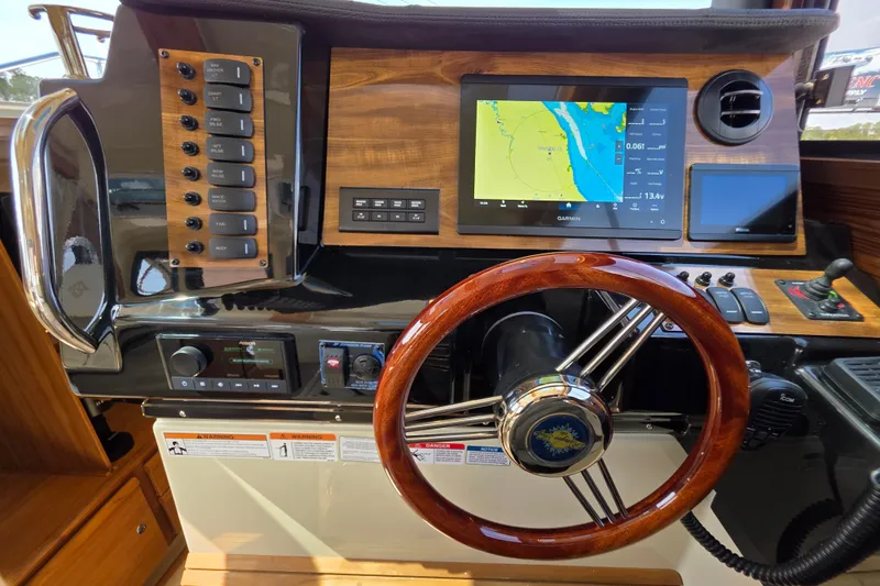 Slide: The Image of 2026 Ranger Tugs R-27 helm with Garmin navigation, wooden steering wheel, and control panel. - 14