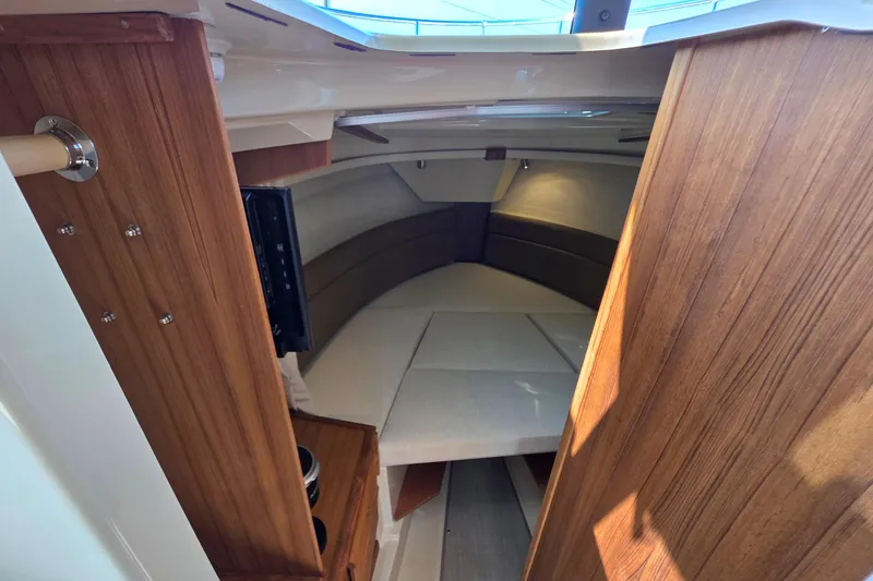 Slide: The Image of 2026 Ranger Tugs R-27 cabin interior with wood finish and cozy sleeping area. - 16