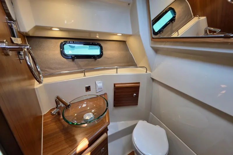 Slide: The Image of 2026 Ranger Tugs R-27 boat bathroom with glass sink and porthole window. - 18