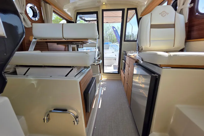Slide: The Image of Interior of 2026 Ranger Tugs R-27 boat, featuring seating and kitchenette. - 23