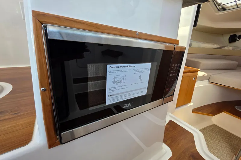 Slide: The Image of 2026 Ranger Tugs R-27 interior featuring a built-in microwave with wooden accents. - 27